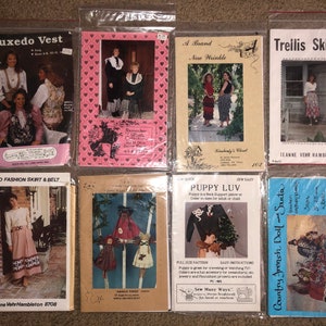 May include: A collection of eight vintage sewing patterns, including a tuxedo vest, a skirt and belt, a doll, a puppy, and a skirt. The patterns are in plastic bags and have various colors and designs.