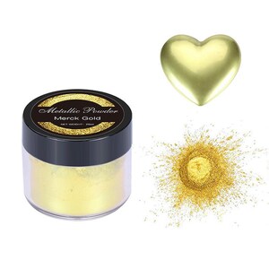 May include: A small jar of gold metallic powder labeled "Metallic Powder Merck Gold" with a net weight of 20ml. A heart-shaped pile of gold powder and a gold heart are shown.