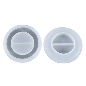 May include: Two clear, circular silicone molds for resin casting. One mold has a dark gray ring around the outer edge. The other mold has a horizontal divider across the center.
