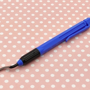 May include: A blue and black plastic scraper tool with a curved blade. The tool has a retractable handle.