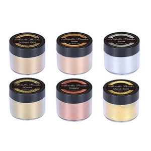 May include: Six small jars of metallic powder in various colors, including antique gold, gold, silver, bronze, copper, and morck gold. Each jar has a black lid and a label that reads "Metallic Powder" and the color of the powder.