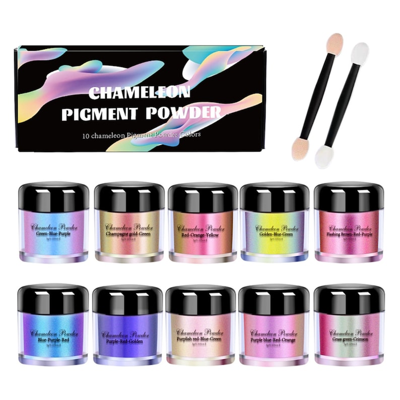 May include: Ten small jars of chameleon pigment powder, each with a different color combination. The jars are arranged in two rows of five. The colors are green-blue-purple, champagne gold-green, red-orange-yellow, golden blue-green, pinking rose-red-purple, blue-purple-red, purple-red-golden, purplish red-blue-green, purple blue-red-orange, and cream green-green. The jars are labeled with the color combinations. The image also includes two small white makeup sponges on black sticks.