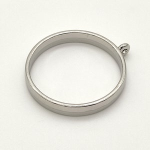 May include: Silver metal ring with a small loop on one side. The ring is smooth and has a polished finish.