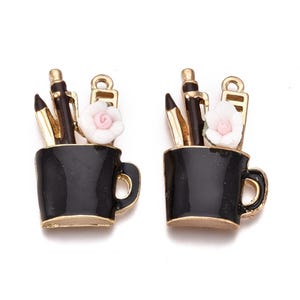 May include: A pair of gold-tone earrings with black enamel cups and white ceramic flowers. Each cup contains a set of gold-tone pens and pencils.