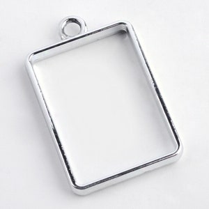 Peut inclure: Cadre de pendentif en métal argenté de forme rectangulaire avec une petite boucle en haut pour l'accrocher.