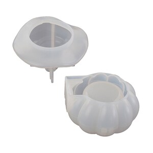 May include: Two white silicone moulds for making candles. One mould is shaped like a pumpkin and the other is shaped like a hat.