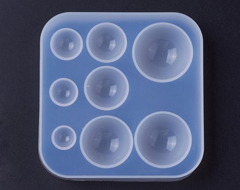 May include: A clear silicone mold with seven round cavities of varying sizes. The mold is designed for creating resin spheres.