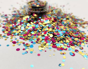 May include: A pile of colorful glitter in gold, blue, and pink. The glitter is in the shape of small circles.