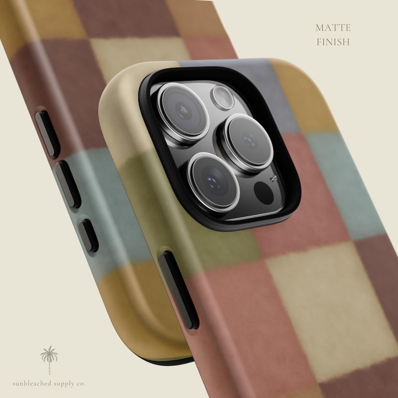 This phone case features a soft, muted checkerboard pattern made up of square blocks in earthy tones—dusty pink, cream, sage green, mustard yellow, brown, and light blue. Each square has a slightly textured, vintage look, creating a warm, cosy, quilt-like aesthetic. No additional graphics or text appear on the case the buyer receives.