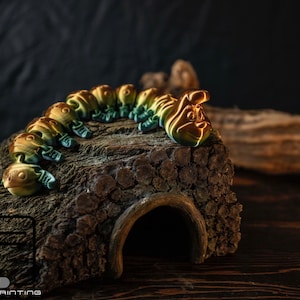 Peut inclure: Une figurine de chenille imprimée en 3D dorée et verte rampante sur une bûche de bois avec un espace creux. La chenille a une surface texturée et un design détaillé.