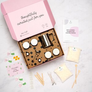 May include: A pink box with the text "thoughtfully curated just for you" on the lid. The box contains a soy candle making kit with all the necessary supplies, including soy wax flakes, wicks, jars, a thermometer, and a pouring pitcher. The kit also includes instructions and stickers.