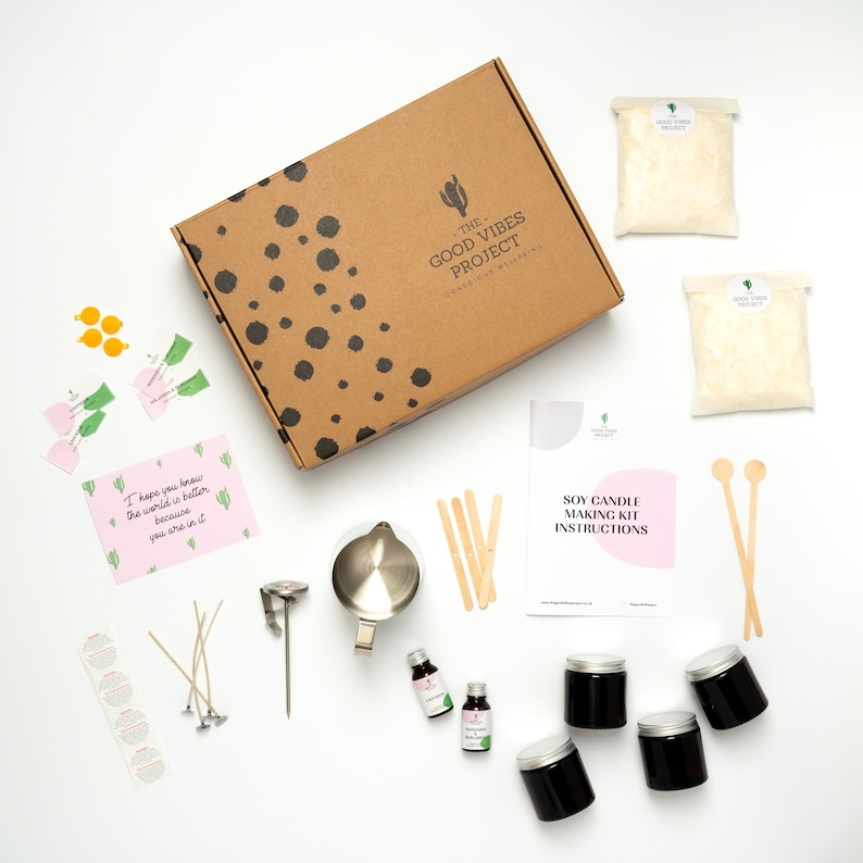 May include: A soy candle making kit with all the supplies needed to create your own candles. The kit includes soy wax flakes, wicks, essential oils, glass jars, and instructions. The kit is packaged in a brown box with black polka dots and the words "The Good Vibes Project" printed on it.