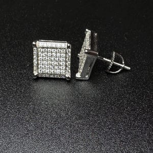 May include: A pair of silver square-shaped earrings with clear cubic zirconia stones.