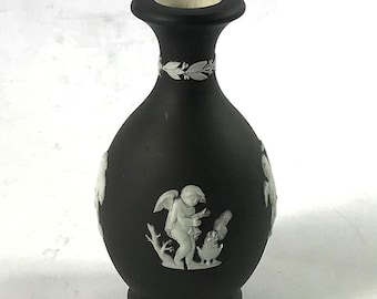 May include: A black ceramic vase with white bas-relief decoration of a cherub and a rooster.