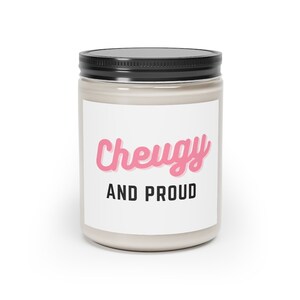 Puede incluir: Un tarro de vela blanco con tapa negra. La etiqueta en el tarro dice "Cheugy and Proud" en letras rosa y negras.