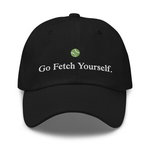 Puede incluir: Gorra de béisbol negra con bordado blanco que dice "Go Fetch Yourself." Una pelota de tenis verde está bordada encima del texto.