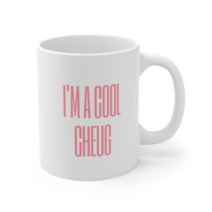 Puede incluir: Taza de café de cerámica blanca con una inscripción rosa que dice "I'm a cool cheug".