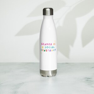 May include: White stainless steel water bottle with a rainbow colored graphic that says "Gender is a social construct".