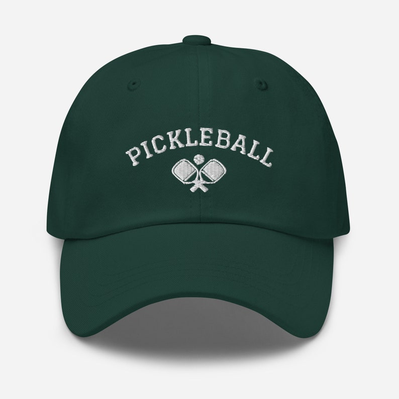 May include: A dark green baseball cap with white embroidery that reads "Pickleball" and features a pair of crossed pickleball paddles with a ball.