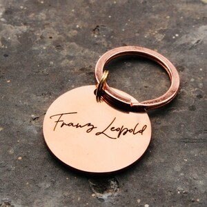 May include: A copper-colored keychain with a round tag engraved with the name "Franz Leopold" in a cursive font.