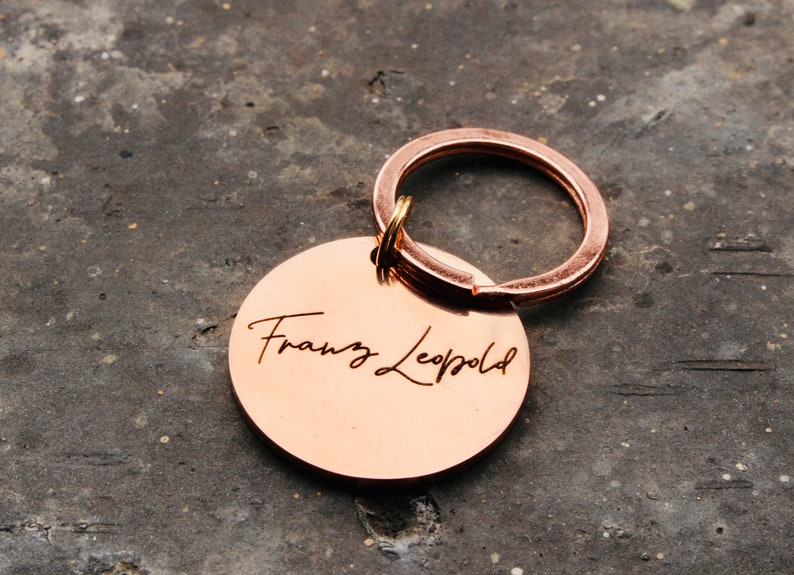 May include: A copper-colored keychain with a round tag engraved with the name "Franz Leopold" in a cursive font.