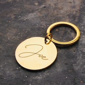 May include: Gold-colored keychain with a round tag engraved with the name "Zoe" in cursive.