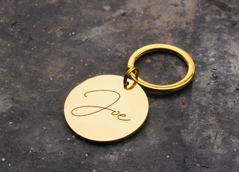 May include: Gold-colored keychain with a round tag engraved with the name "Zoe" in cursive.