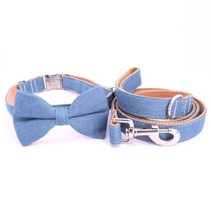 Könnte beinhalten: Ein blaues Hundehalsband und eine Leine aus Denim mit passendem Fliege. Das Halsband hat eine silberne Schnalle und die Leine einen silbernen Haken.