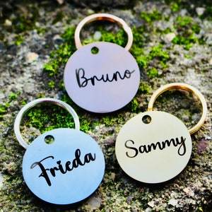 May include: Three round metal keychains with engraved names. The keychains are silver, gold, and rose gold. The names are "Bruno", "Sammy", and "Frieda".