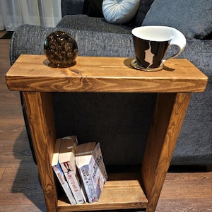 May include: A stained wooden side table with a decorative glass orb and a black and white coffee cup. Three books are visible on the lower shelf. The table is 61 cm long, 30 cm wide, and 51 cm tall.