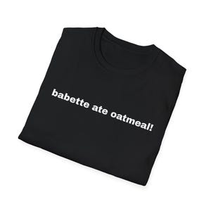 Puede incluir: Camiseta negra con el texto blanco "babette ate oatmeal!". La camiseta está doblada y se muestra sobre un fondo blanco. La camiseta es una prenda informal.