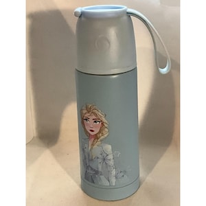May include: A light blue insulated water bottle featuring a cartoon image of a princess. The bottle has a matching light blue lid with a handle. The bottle is cylindrical and appears to be made of metal.