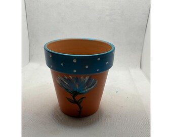 Maceta de arcilla pintada a mano con borde de lunares azules y diseño floral
