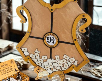 May include: A wooden guest book alternative with a shield design, featuring a gold border and black accents. The center displays a "9 3/4" emblem and small paper envelopes. A matching box and sign are also present.