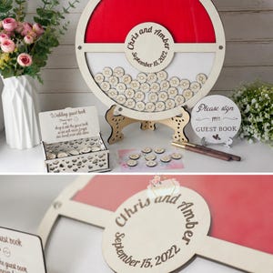 Puede incluir: Un libro de visitas de boda de madera con un dise&ntilde;o rojo y blanco. El marco circular tiene una secci&oacute;n para que los invitados firmen peque&ntilde;as fichas de madera. Los nombres "Chris and Amber" y la fecha "15 de septiembre de 2022" est&aacute;n grabados.
