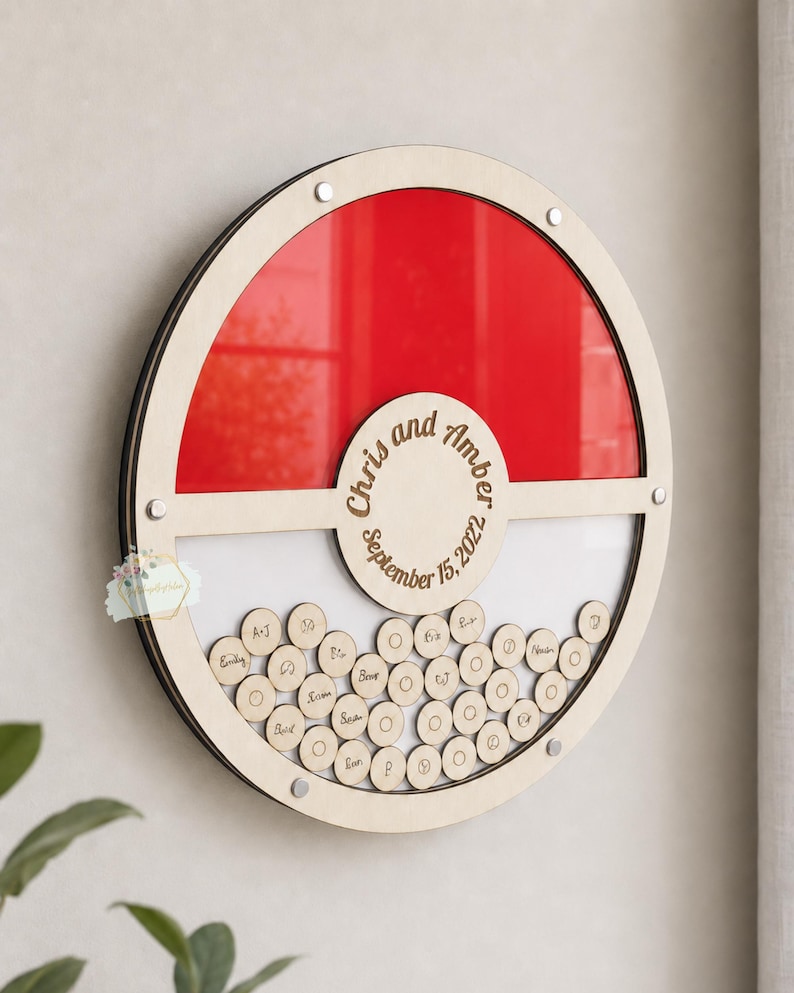 Puede incluir: Un libro de visitas alternativo redondo de madera con un dise&ntilde;o rojo y blanco. La secci&oacute;n superior es roja y la secci&oacute;n inferior es blanca. El centro tiene los nombres "Chris y Amber" y la fecha "15 de septiembre de 2022". Peque&ntilde;os c&iacute;rculos de madera debajo.
