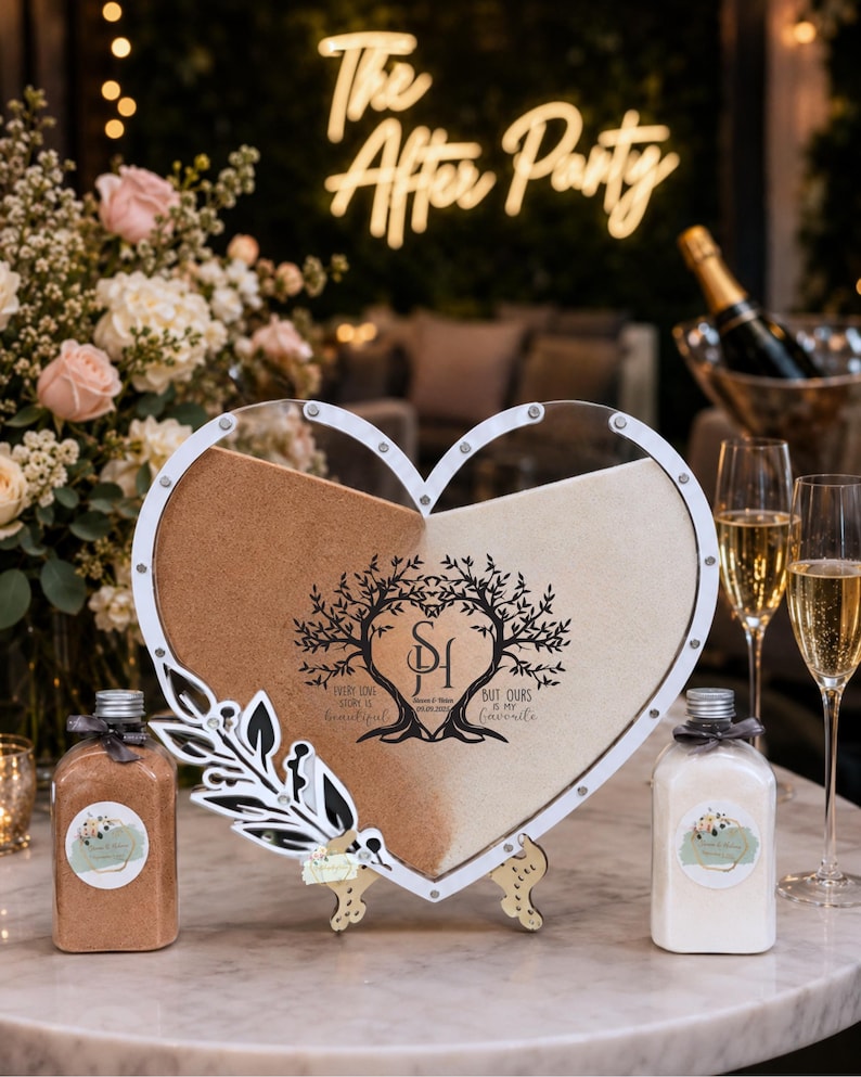 May include: A heart-shaped sand ceremony set with two colours of sand, a decorative frame, and two bottles. The frame has a tree design and the text "Every love story is beautiful, but ours is my favourite." The background includes champagne flutes and a neon sign that says "The After Party."
