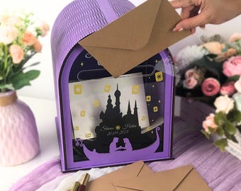 May include: A purple mailbox with a decorative design featuring a silhouette of a castle and a boat. The mailbox has a slot for inserting envelopes. The text "Steven & Helen 20.09.2025" is visible. A hand is inserting a brown envelope.