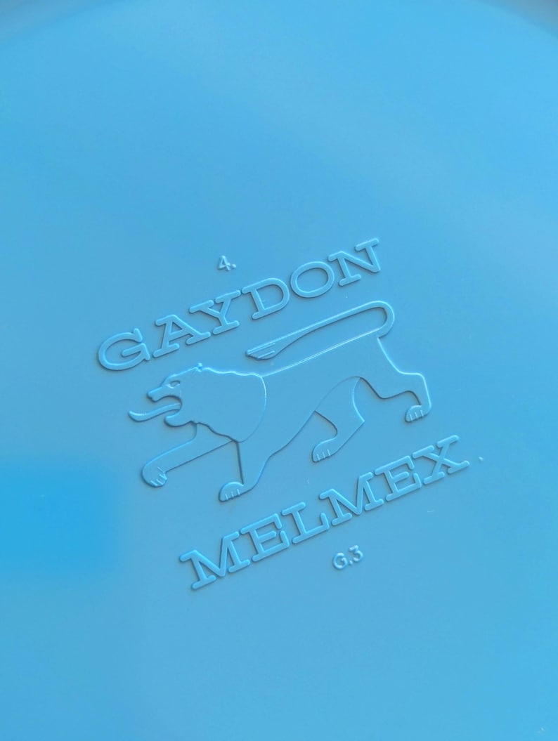 May include: A blue plastic disc with the embossed text "Gaydon 4. Melmex G3" and a stylized lion graphic.