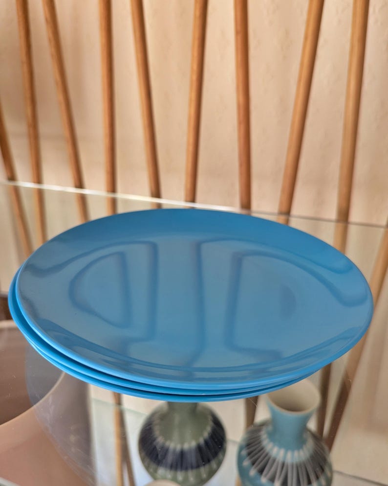 May include: A stack of three blue ceramic plates. The plates are round and have a smooth, glossy finish.