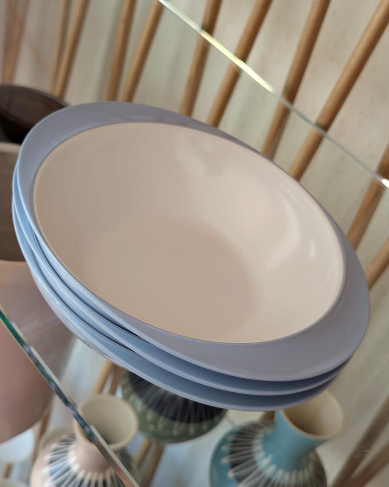 May include: Three blue and white ceramic bowls stacked on top of each other. The bowls have a light blue rim and a white interior.