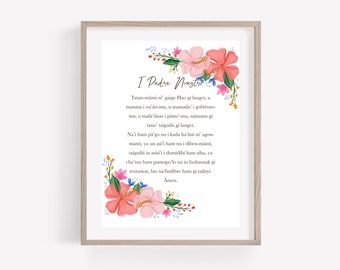 Op de afbeelding: Een printbaar wandkunstontwerp met een bloemige rand met roze en witte bloemen. De tekst in het midden luidt "I Padre Nuestro" en bevat een traditioneel katholiek gebed in het Chamorro.