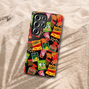 May include: A black smartphone case featuring a colorful pattern of various snack food packages, including bags labeled Chips Pika, Ya Ya cups, and other food illustrations. The case has a cutout for a multi-lens camera system on the back.