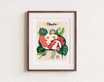 May include: A framed art print featuring a Chamoru Breakfast illustration. The graphic shows a dark blue plate with two fried eggs, sliced meat, bacon, and a red hot sauce bottle, surrounded by green tropical leaves, a rainbow, and small icons.