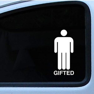 May include: White vinyl decal of a stick figure with the word "GIFTED" below. The decal is applied to a car window, with the black interior visible through the glass. The design is simple and bold.