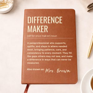 May include: Brown leather journal with the words "DIFFERENCE MAKER" in large, bold letters. The journal includes a definition and a personalized name, "Mrs. Brown". A bookmark is visible.