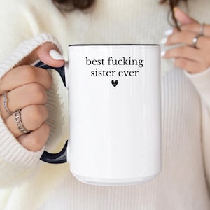 May include: White ceramic mug with a black interior and handle. The mug features the text "best fucking sister ever" in black, with a small black heart below the text. A perfect gift for a sister.