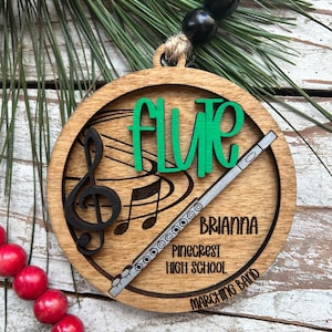 May include: Wooden round ornament with the word "FLUTE" in green, a black treble clef, and a silver flute illustration. The ornament includes the name "Brianna", "Pinecrest High School", and "Marching Band".