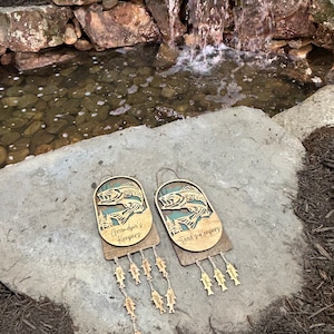 May include: Two wooden fish-shaped wall hangings with the text "Grandpa's Keepers" and "Dad's Keepers" on them. Each hanging has a string of smaller fish-shaped charms hanging from it.