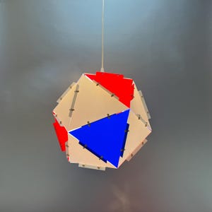 May include: A geometric pendant light fixture with a white, red, and blue design. The light is made of multiple triangular panels that are connected together.
